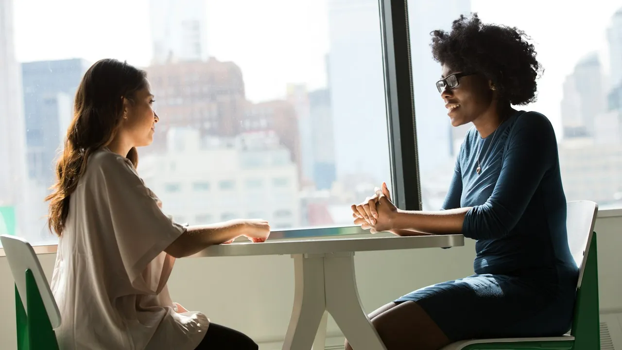 Dos mujeres conversando tranquilamente sentadas junto a una mesa