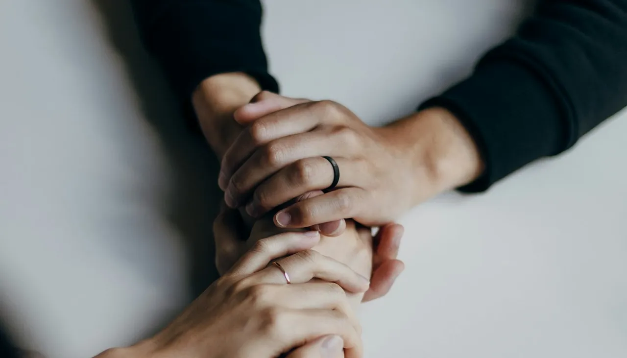Dos personas tomadas de la mano sobre una mesa en señal de apoyo