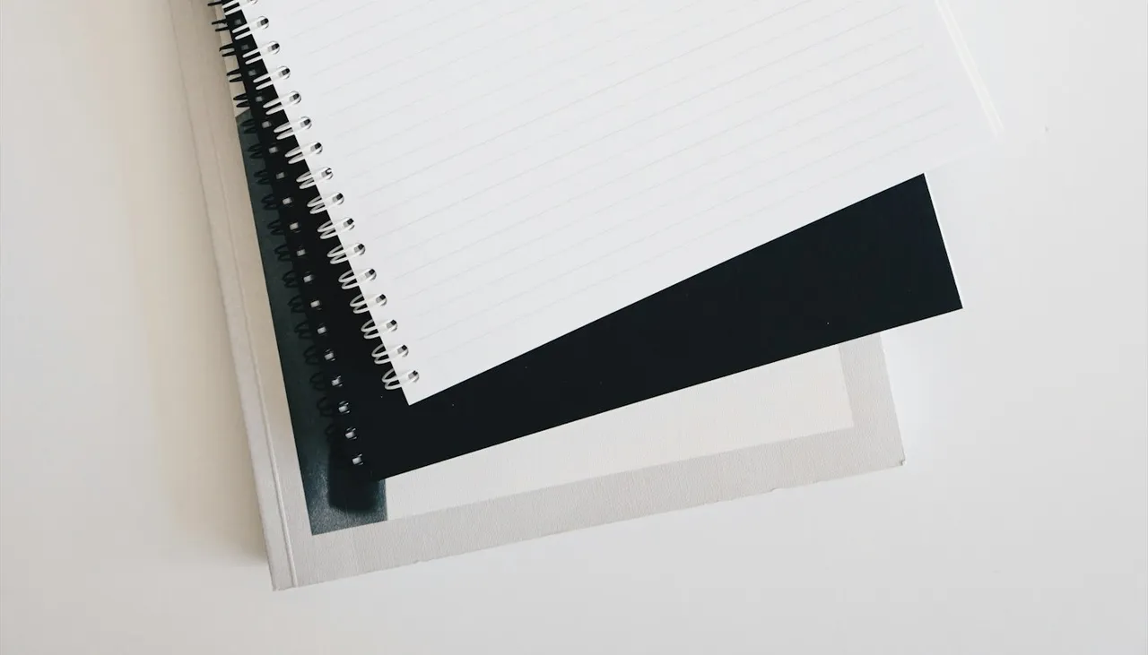 Cuaderno espiral en blanco junto a un teclado y un lápiz