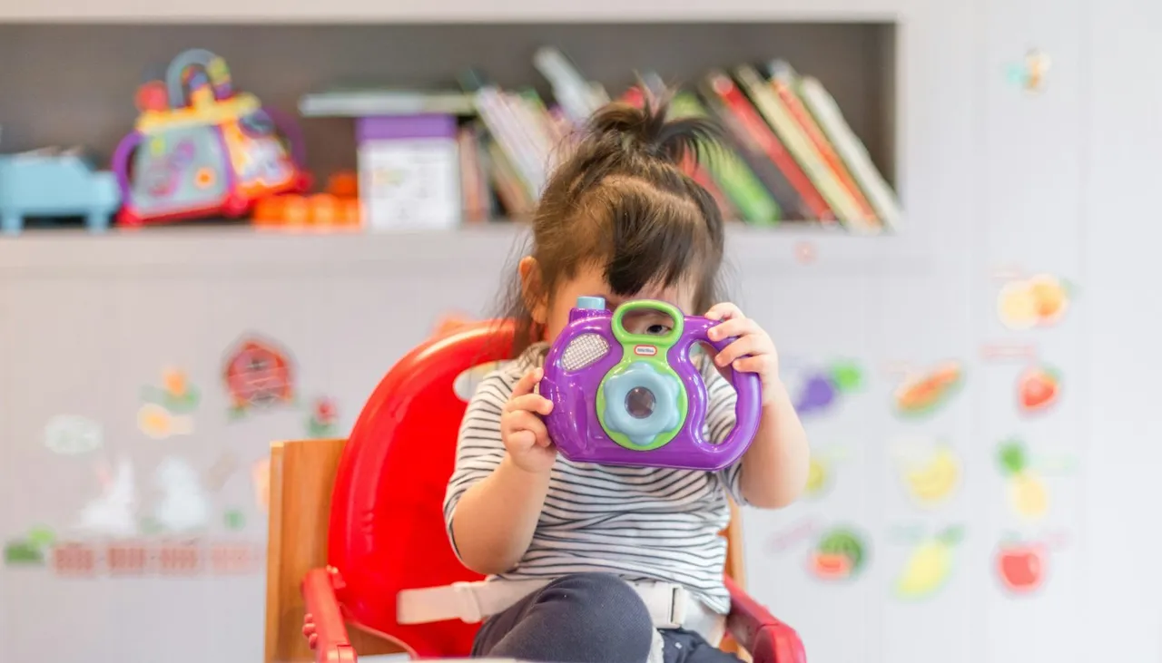 Niña jugando con una cámara de juguete de colores