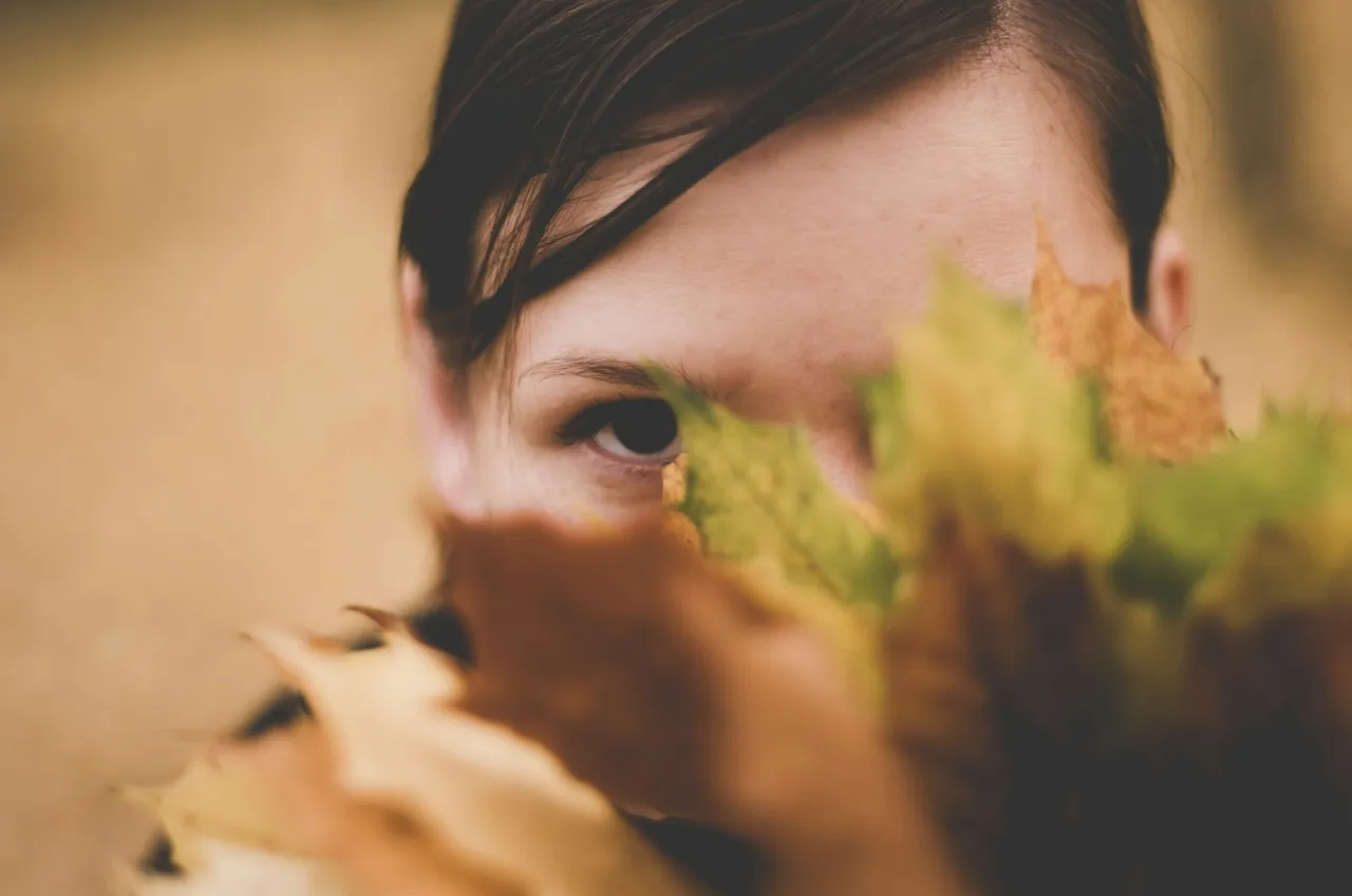 Persona ocultando su rostro detrás de unas hojas