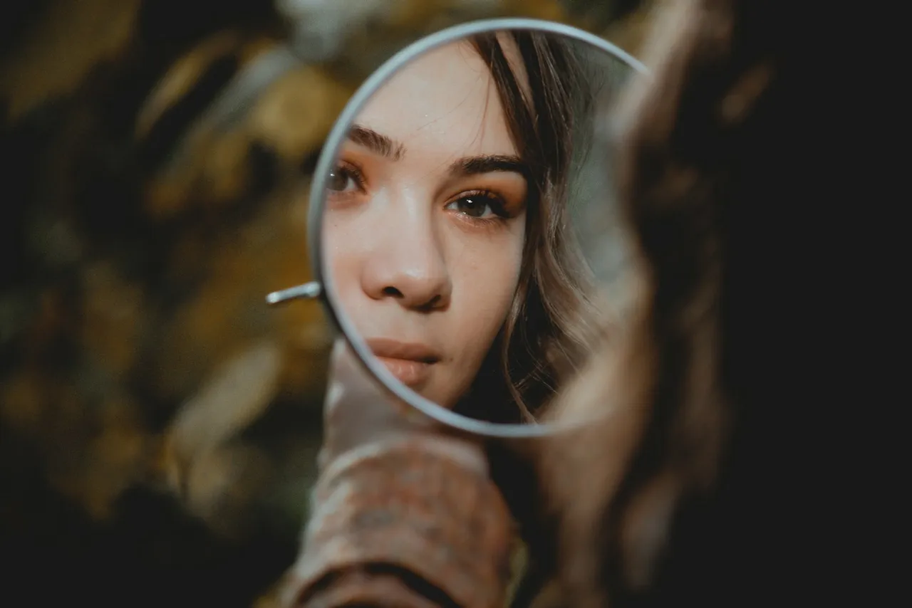 Mujer mirando su reflejo en un espejo de mano